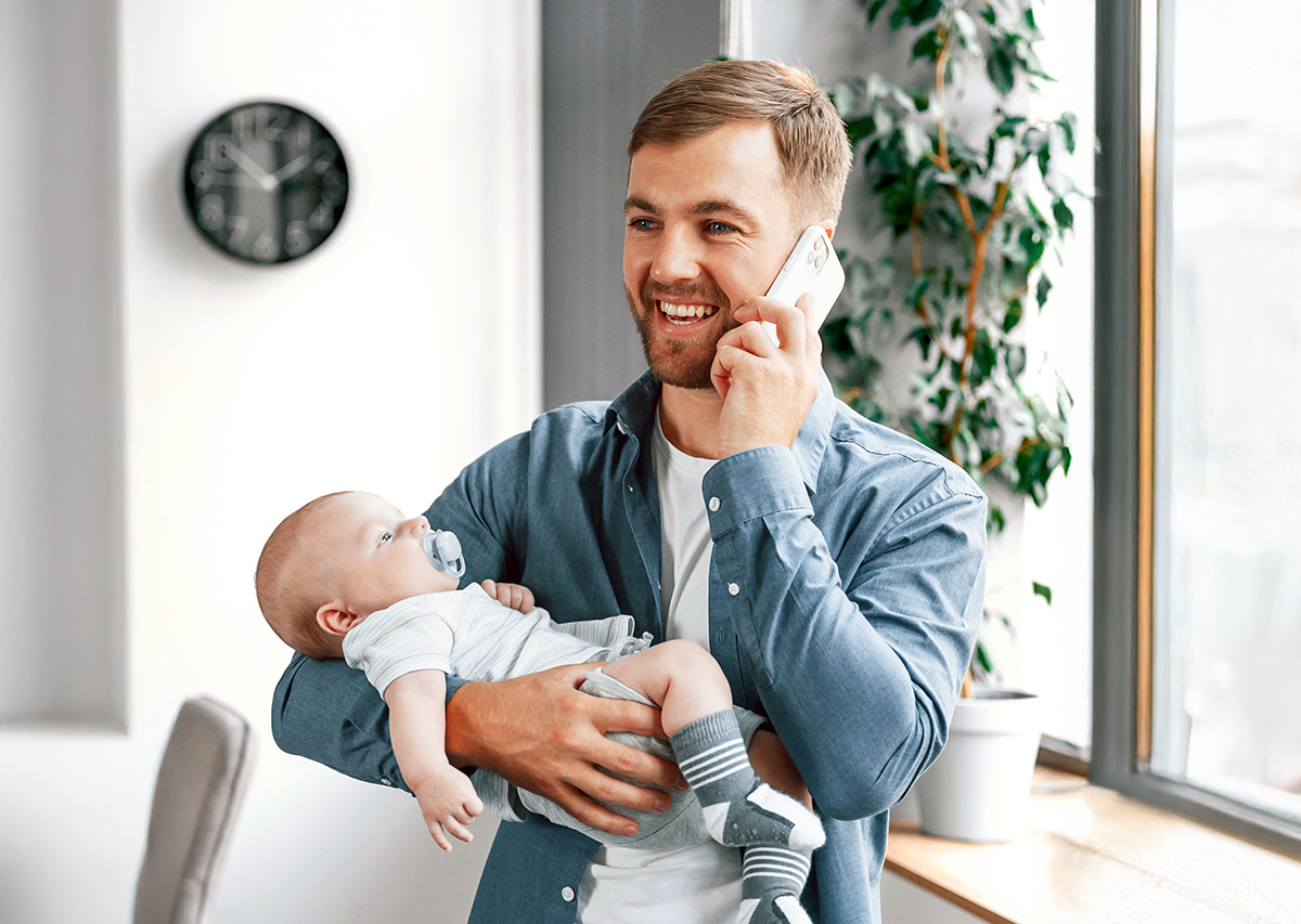 Man talking on phone at home while holding baby